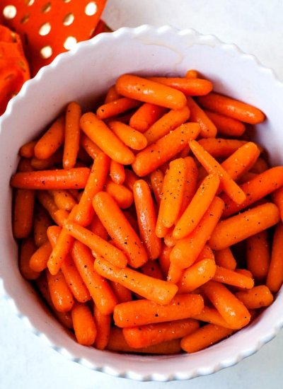 Overhead picture of glazed carrots in a white serving bowl.