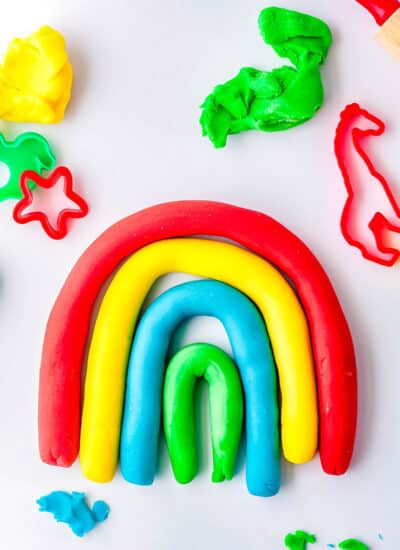 Colorful strands of playdough made into a rainbow shape.