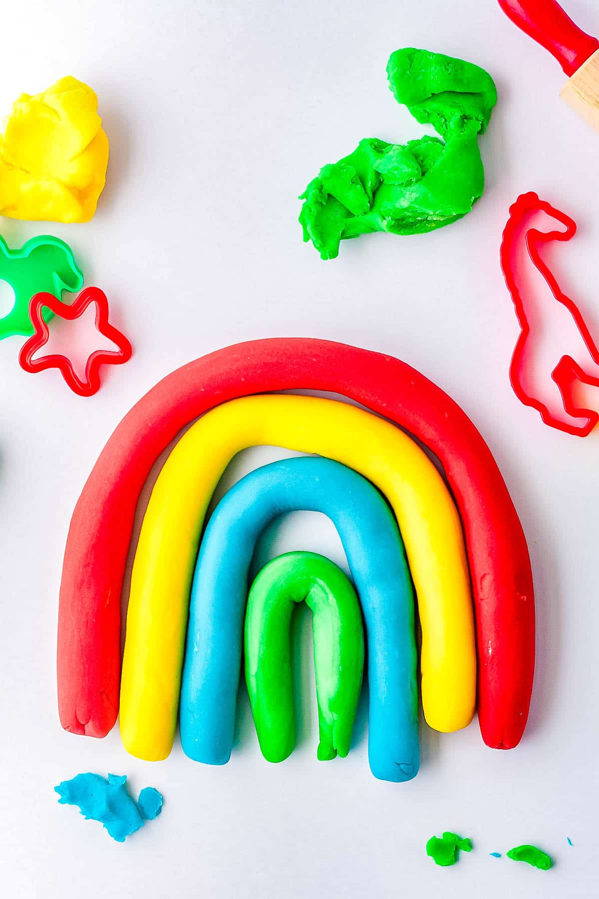 Colorful strands of playdough made into a rainbow shape. 