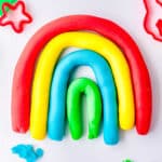 Colorful strands of playdough made into a rainbow shape.