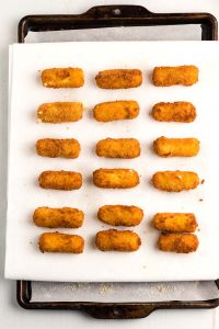 Place the fried cheese sticks on a paper towel-lined baking sheet to drain.