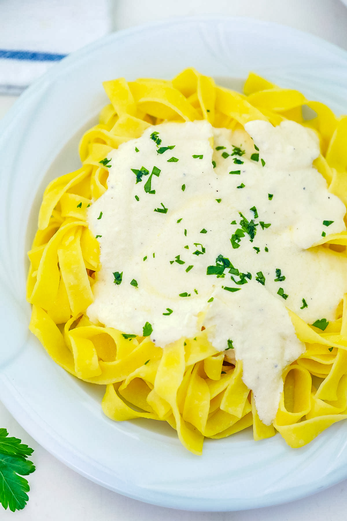 An overhead picture of the finished Fettuccine Alfredo on a white plate.