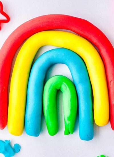 Colorful strands of playdough made into a rainbow shape.