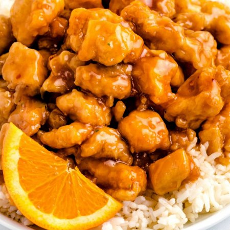 Close up picture of orange chicken with a slice of orange.