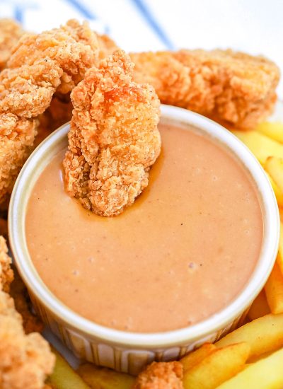 An overhead picture of the finished Copycat Chick-Fil-A Sauce with a chicken strip wing dipped into it.