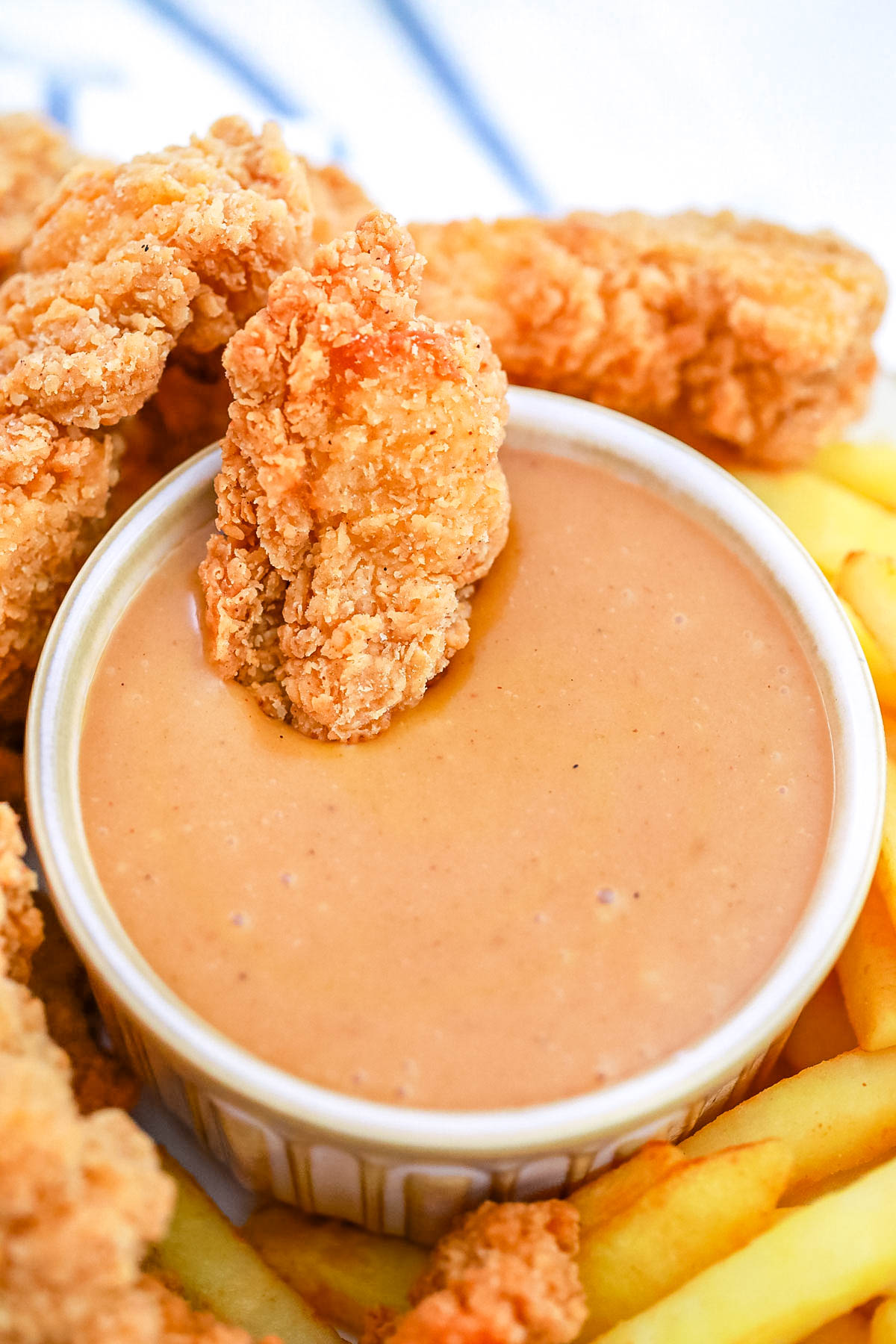 An overhead picture of the finished Copycat Chick-Fil-A Sauce with a chicken strip wing dipped into it.