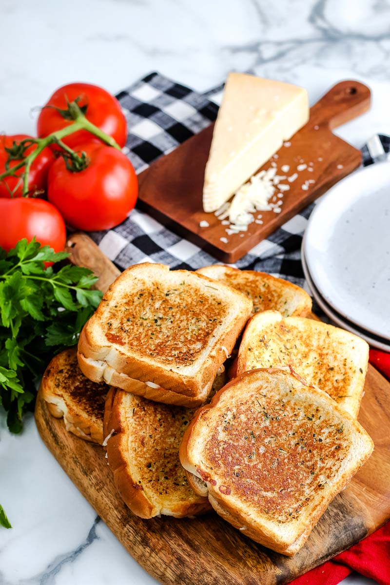 6 Pizza Grilled Cheese Sandwiches piled on top of each other on a wooden cutting board.