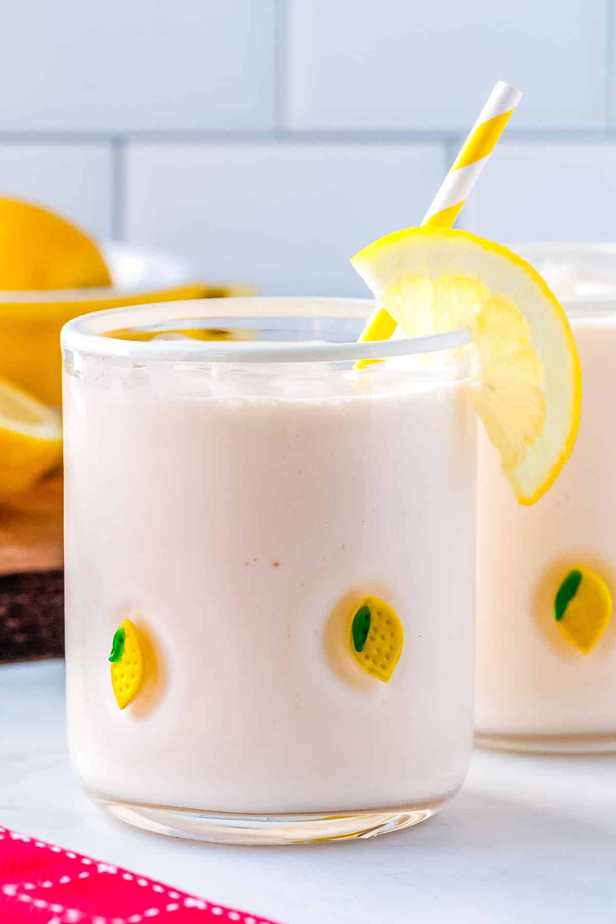 The frosted lemonade poured into a clear glass with a paper straw in it.
