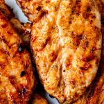 Close up picture of Grilled BBQ Chicken Breasts on a white plate.
