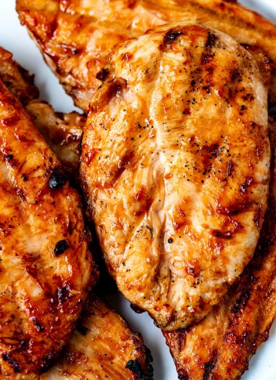 Close up picture of Grilled BBQ Chicken Breasts on a white plate.