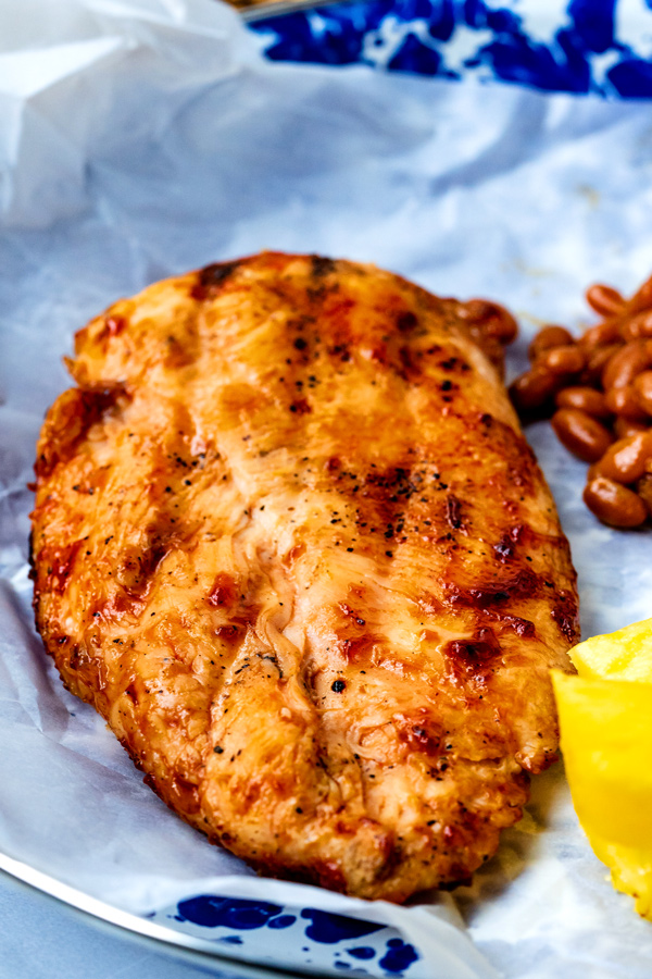 A grilled boneless skinless chicken breast on a blue plate.