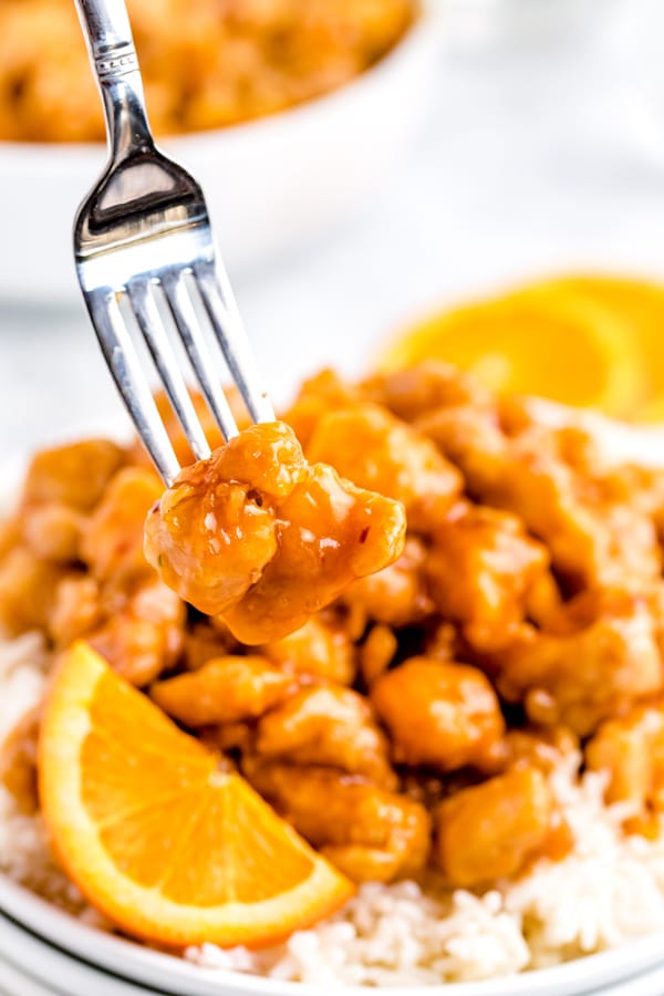 A fork picking up a piece of Panda Express Orange Chicken. 