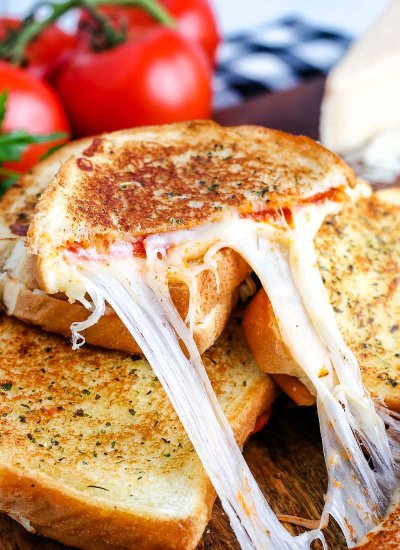 One half of a Pizza Grilled Cheese with a cheese pull coming out of it.