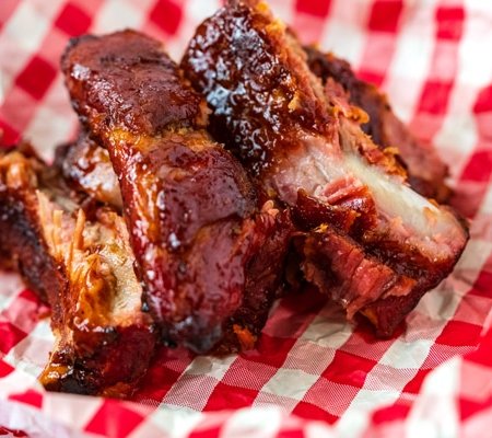 A close up picture of grilled ribs that are cut and stacked on each other.