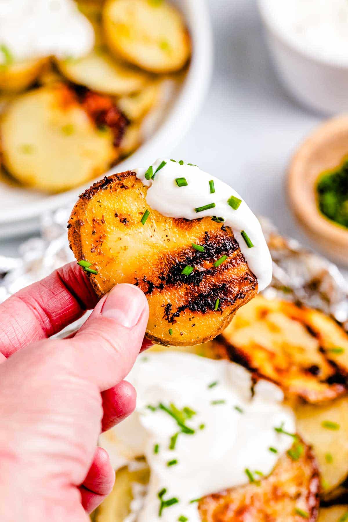 A hand picking up on the the potatoes that were cooked in foil.