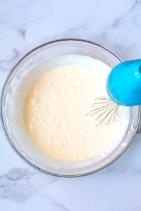 A hand mixer beating the cream cheese, sugar, and vanilla until smooth.