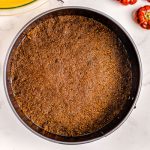 The gingersnap crumb mixture on the bottom of a springform pan.