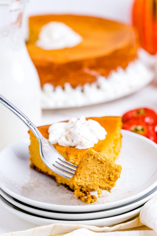 A fork taking a piece out of a slice of cheesecake.