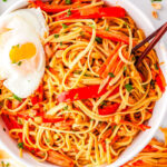 a bowl of thai noodles with a fried egg on top and chopsticks in the bowl