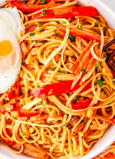 a bowl of thai noodles with a fried egg on top and chopsticks in the bowl