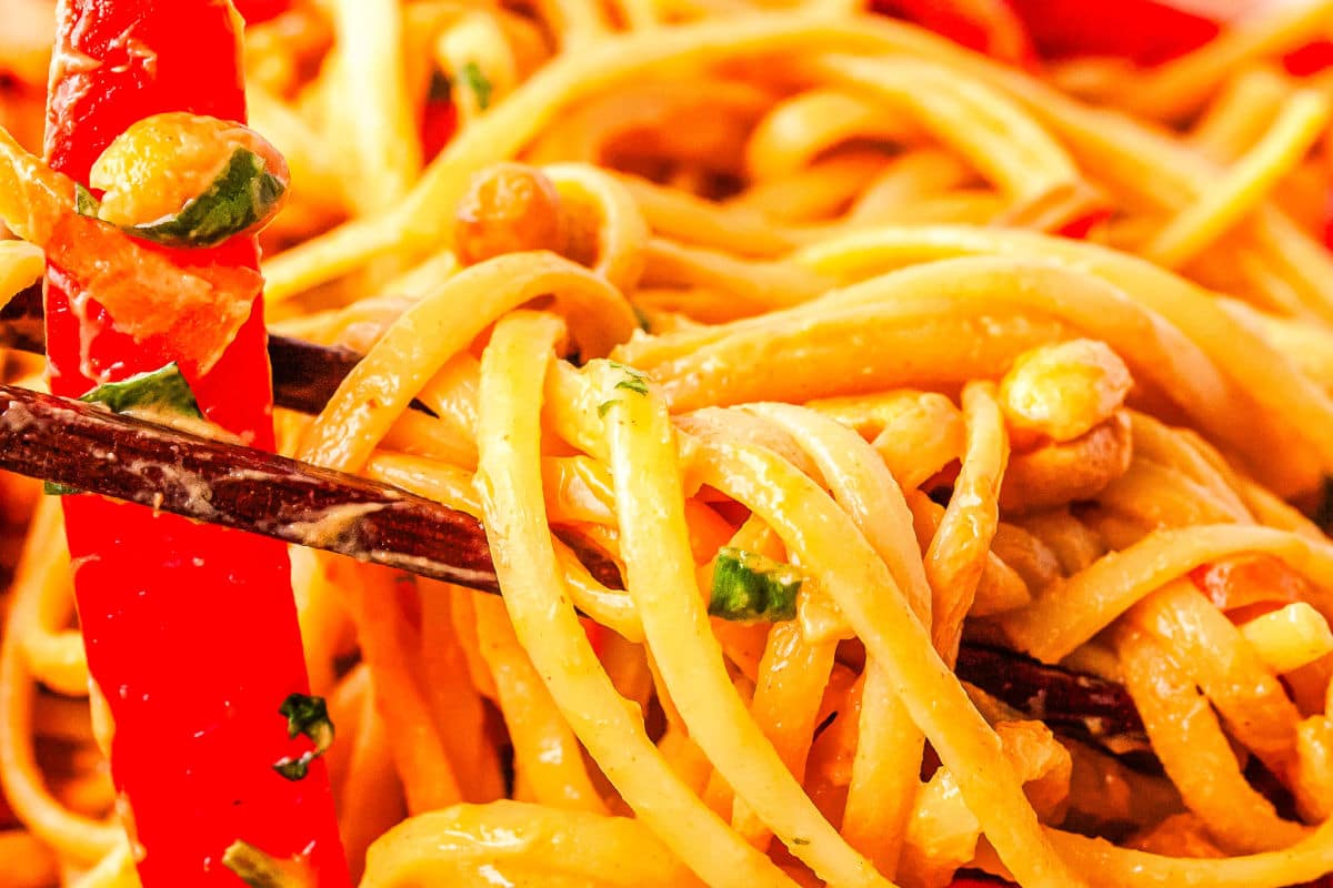 a close up of chopsticks picking up a scoop of thai noodles