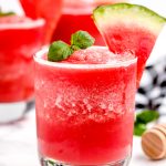 Watermelon smoothie poured into a gladdest and garnished with 2 mint leaves.