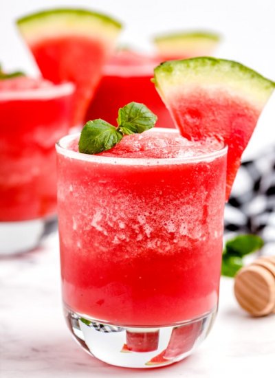 Watermelon smoothie poured into a gladdest and garnished with 2 mint leaves.