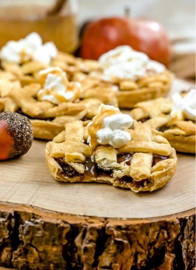 A close up picture of an apple pie ion a wooden serving platter.