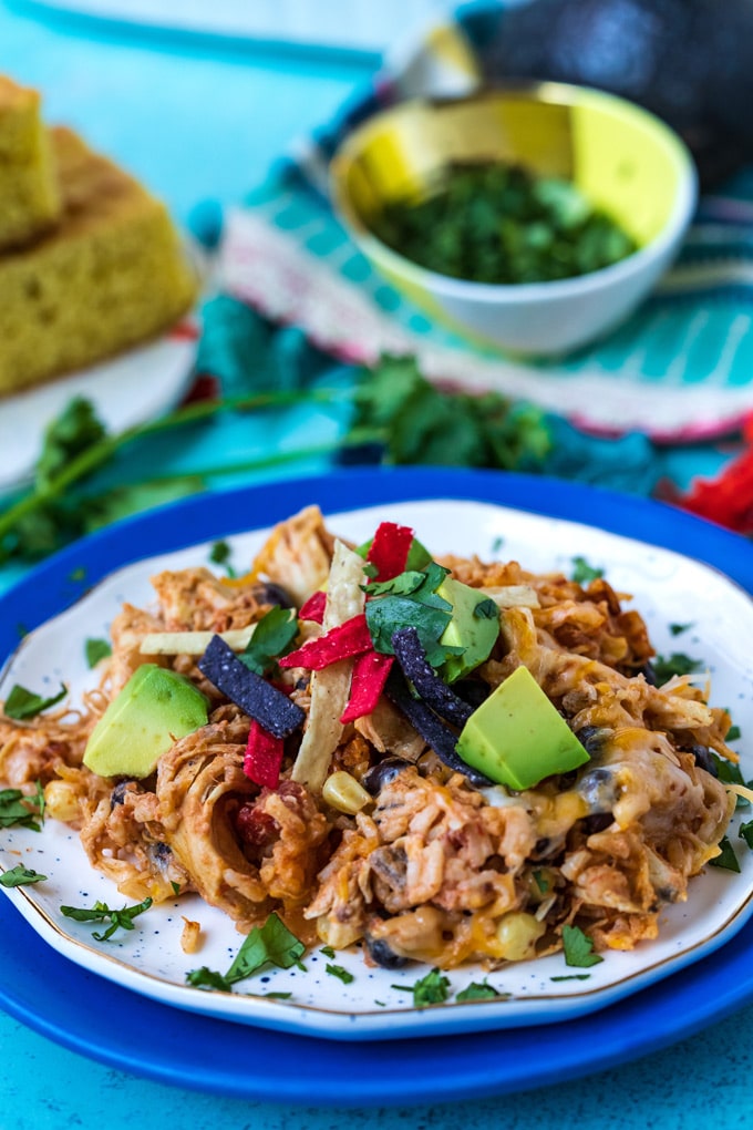 A scoop of the finished casserole on a white plate with avocado and cilantro sprinkled around it.