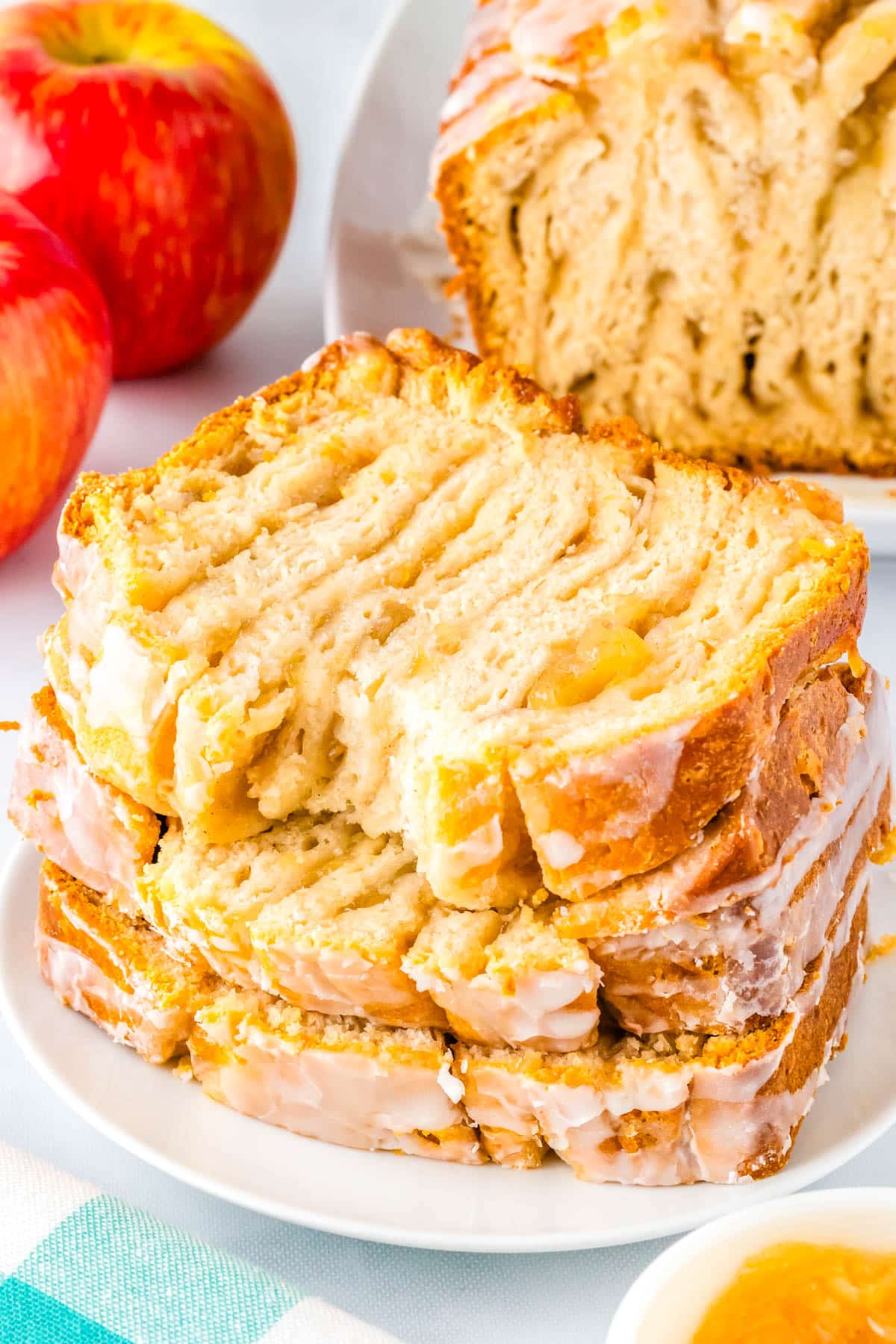 Three slices of apple pie bread stacked on each other with a bite taken out of the top one. 