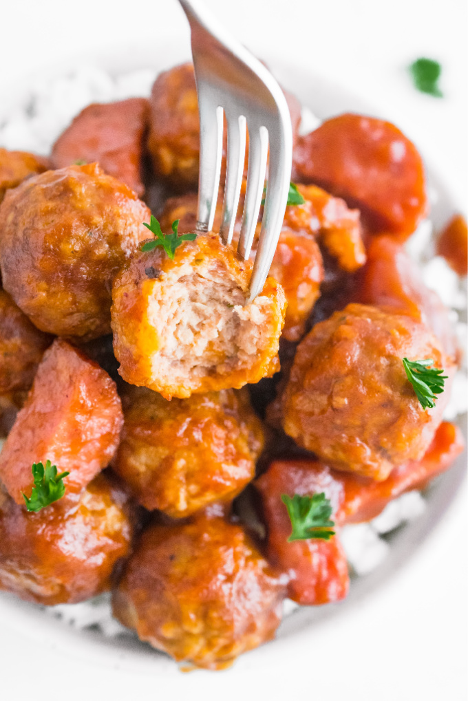 A bowl of crockpot cranberry meatballs with a bite taken out of one.