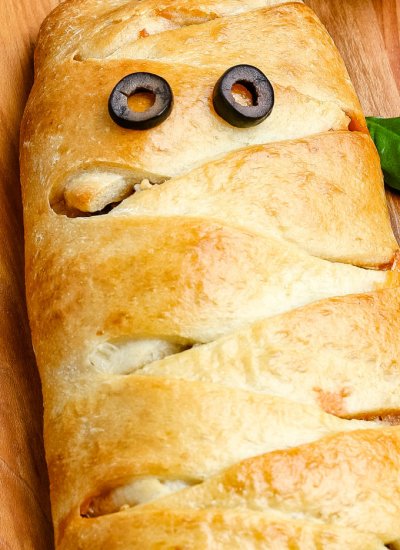 The mummy calzone on a wooden cutting board.