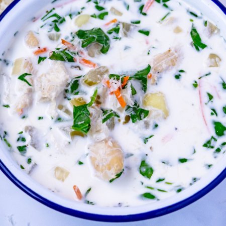 Close up picture of gnocchi soup in a white bowl.