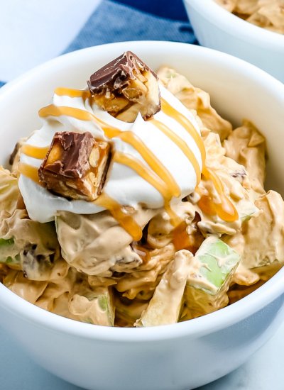 A close up of Snickers Salad with extra cool whip and caramel.