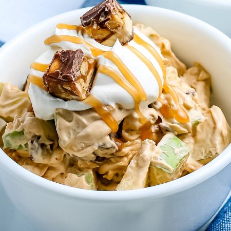 A close up of the finished Snickers salad in a white bowl.