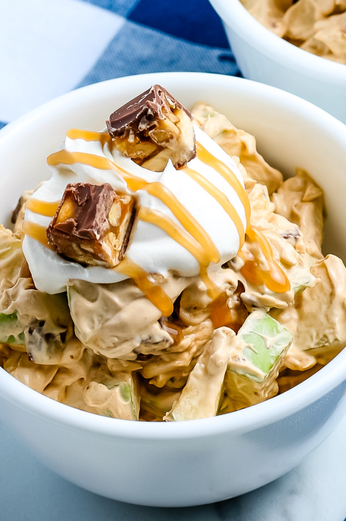 A close up of Snickers Salad with extra cool whip and caramel.