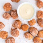 An up close picture copycat cinnamon sugar pretzel bites with a bowl full of cream cheese icing.