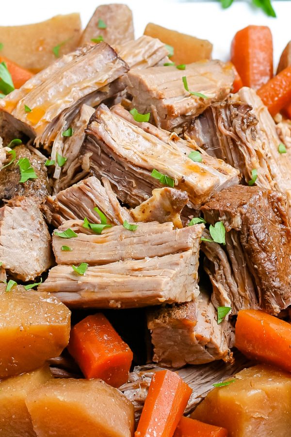 A close up picture of the finished slow cooker pot roast on a white platter. 
