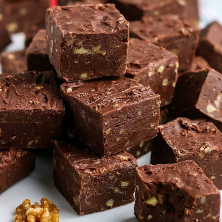 Pieces of chocolate fudge with walnuts stacked on top of each other.