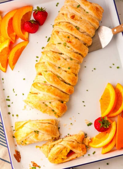 eggs benedict braid on a baking sheet with fruit slices