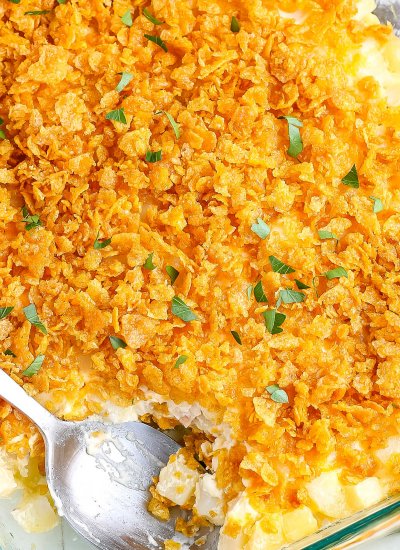 An overhead picture of the finished funeral potatoes with a scoop taken out of it.