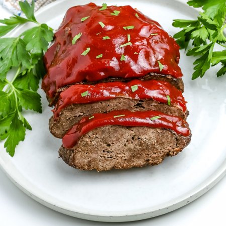 The finished instant pot meatloaf and potatoes on a white platter glazed with ketchup.