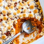 A spoon in the finished sweet potato casserole with marshmallows.