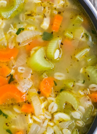 A close up picture of turkey soup in a dark bowl.