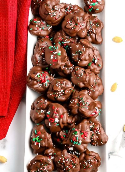 An overhead picture of Christmas Crockpot Candy on a white serving platter and a red kitchen towel nearby.