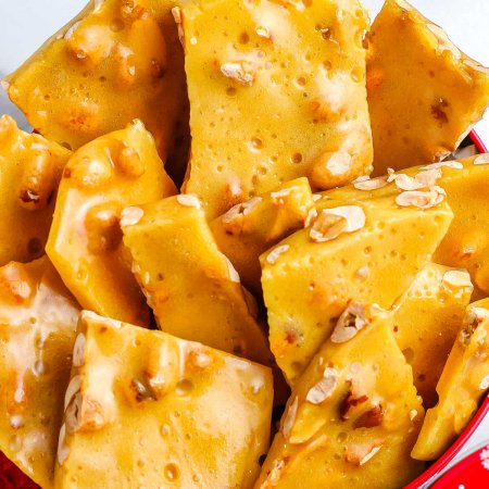 A close up picture of peanut brittle in a decorative gifting tin.