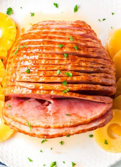a top view of honey baked ham on a plate with pineapple slices