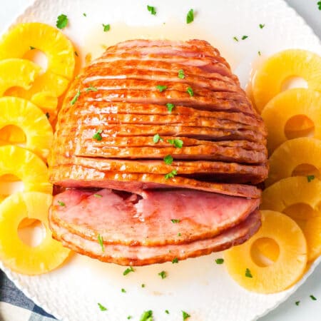 a top view of honey baked ham on a plate with pineapple slices