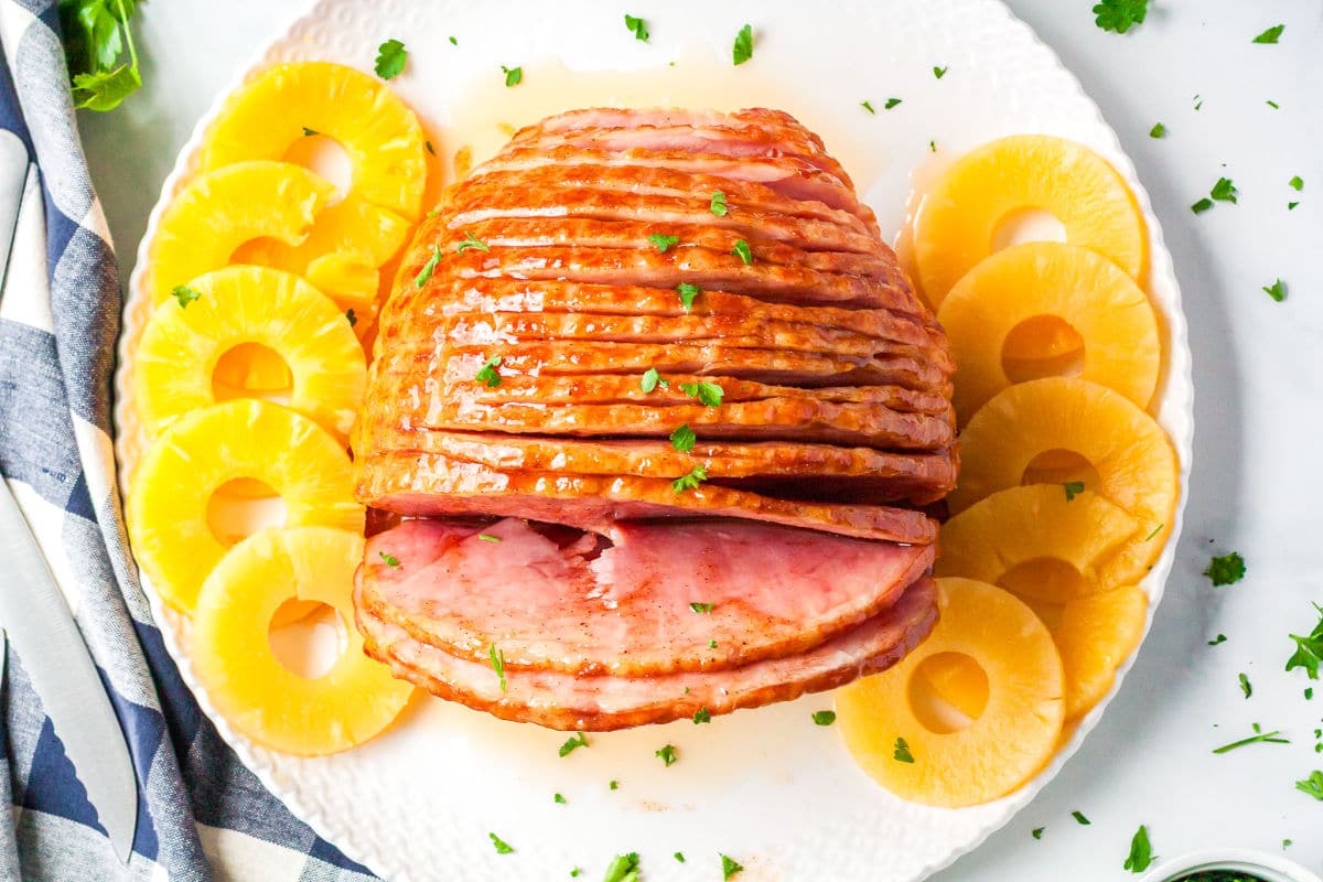a top view of honey baked ham on a plate with pineapple slices