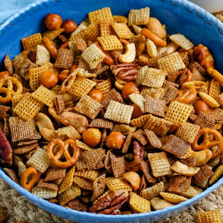 A close up picture of the finished Chex Mix in a blue bowl.